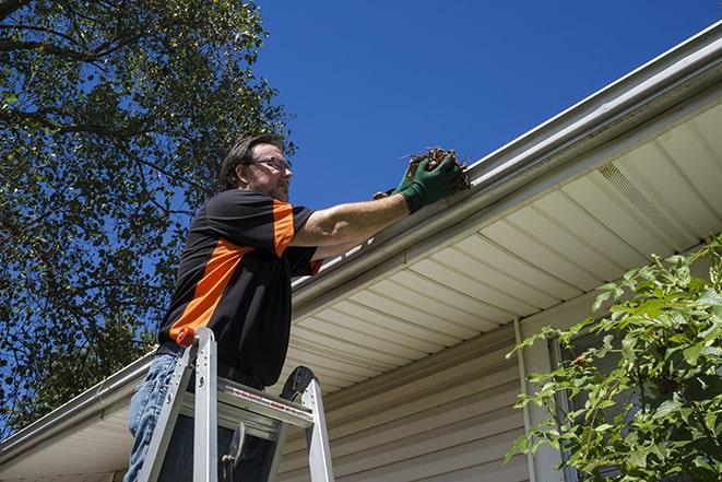 worker repairing a damaged gutter on a residential roof in Brackney PA